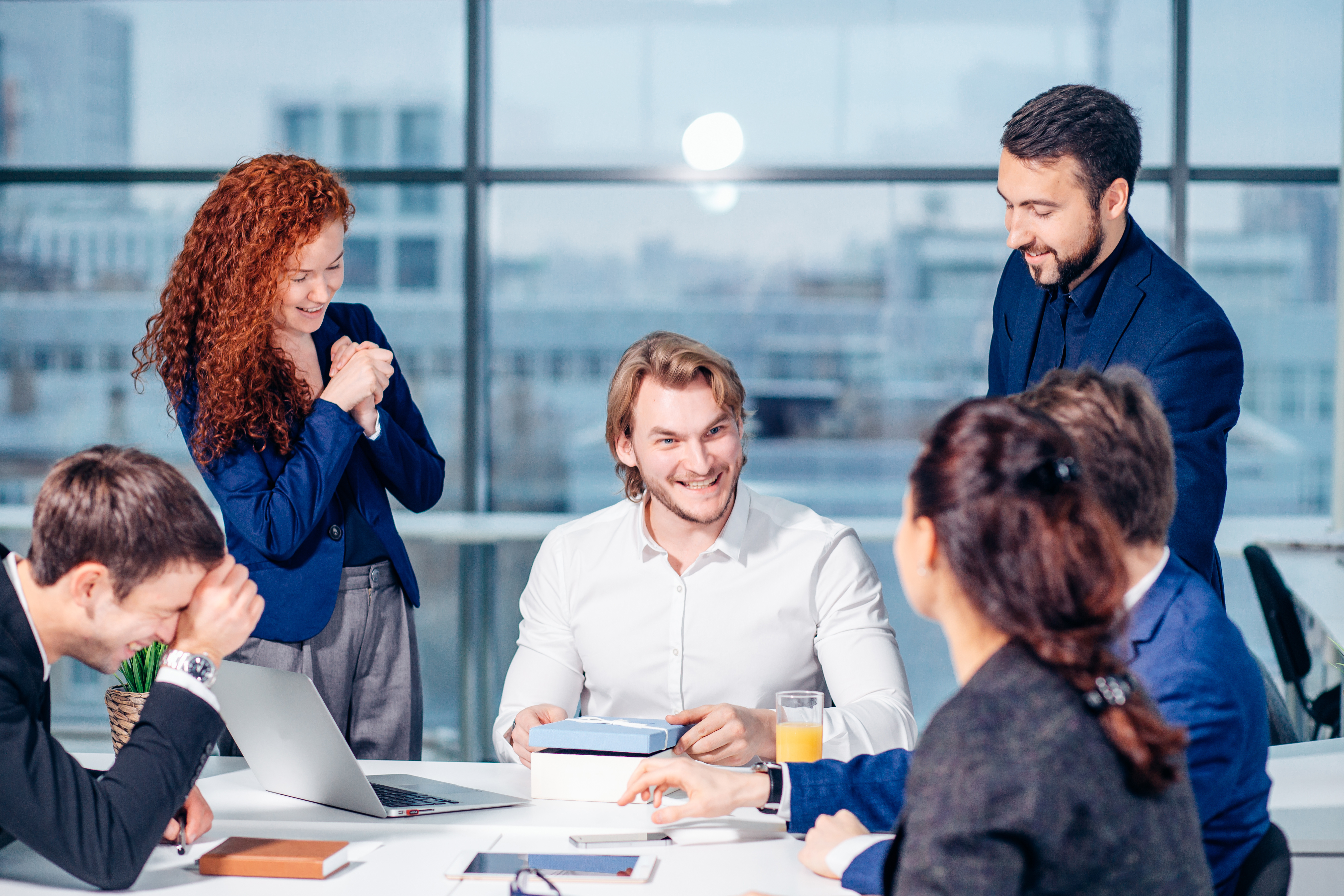 Group of employees smiling as they give a gift